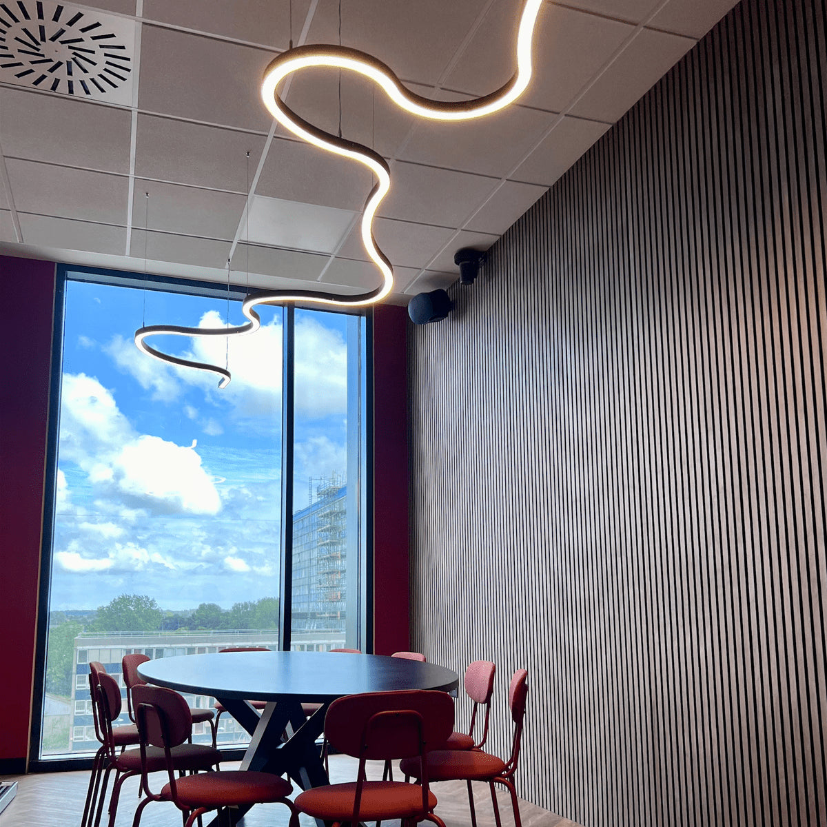 The Curva Wiggle light installed in a conference room pairing beautifully with slatted walls.
