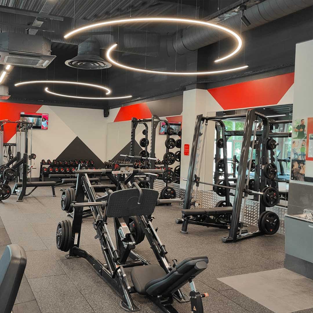 Curved downwards arc suspended LED linear lights installed in a gym.