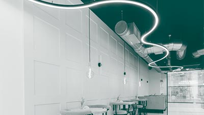 A flowing long linear light running across the ceiling of a cafe.