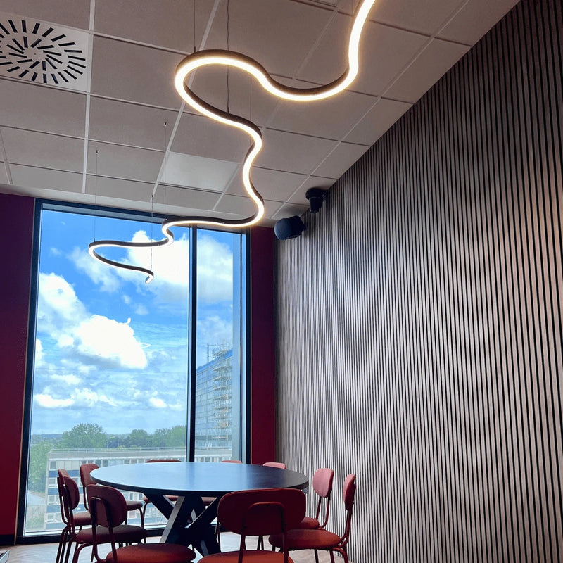A bespoke curved LED ceiling light suspended from a stylish office conference room.