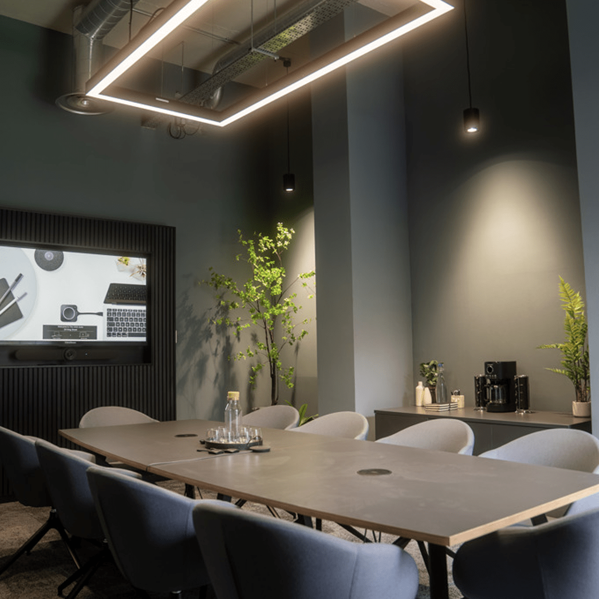 A boardroom with a suspended Estrella Pro rectangular LED linear ceiling light in black installed.