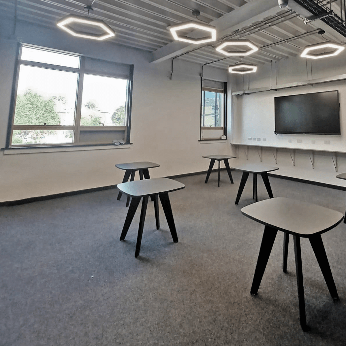 Multiple led hexagon pendant lights installed within a classroom.